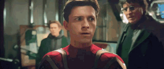 a man in a spiderman costume looks surprised while standing next to another man