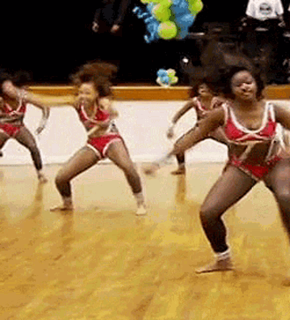 a group of cheerleaders are dancing together on a wooden floor .