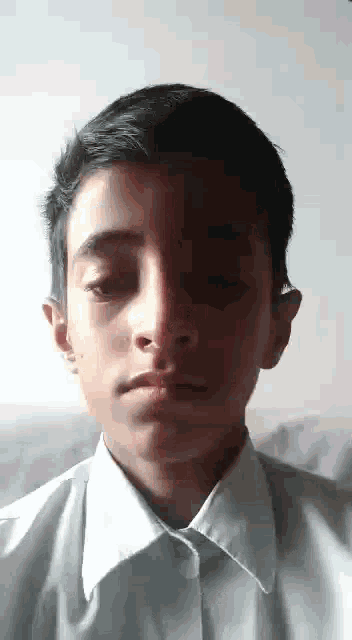 a young boy wearing a white shirt is looking at the camera .
