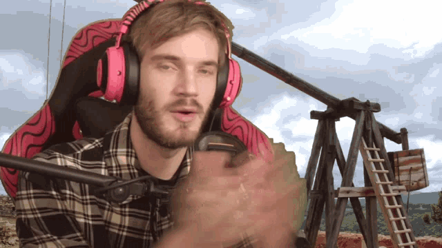 a man wearing headphones and a plaid shirt is sitting in a chair