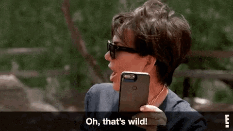 a woman is holding a cell phone in her hand and says `` oh , that 's wild ! ''