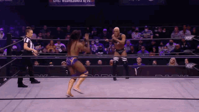 a wrestler is kicking another wrestler in a wrestling ring while a referee watches