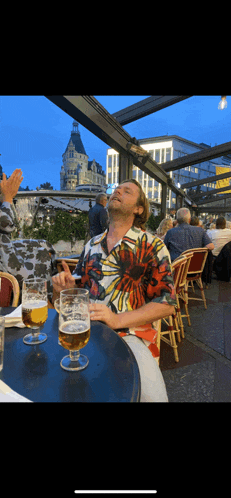 a man sitting at a table with a glass of beer in front of him