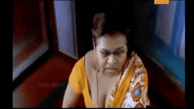a woman wearing glasses and a yellow blouse is sitting on the floor .