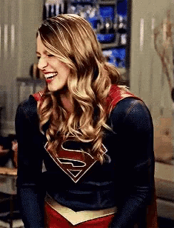 a woman in a superman costume is smiling and laughing