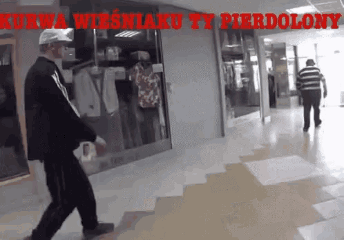 a man walking down a hallway with the words kurwa wiesniaku ty pierdolony written on it