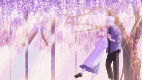 a boy and a girl are standing under a tree with purple flowers