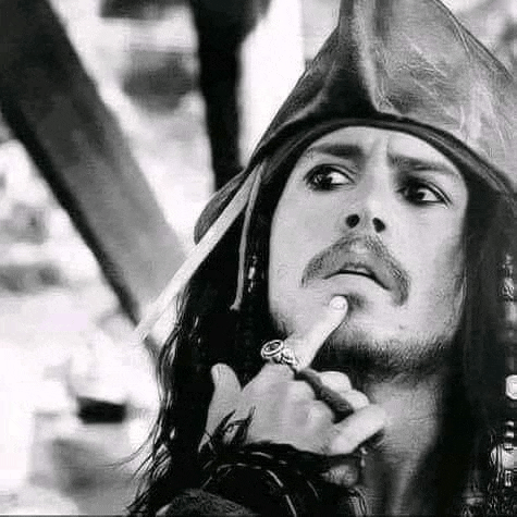 a black and white photo of a man in a pirate hat holding his finger to his chin .
