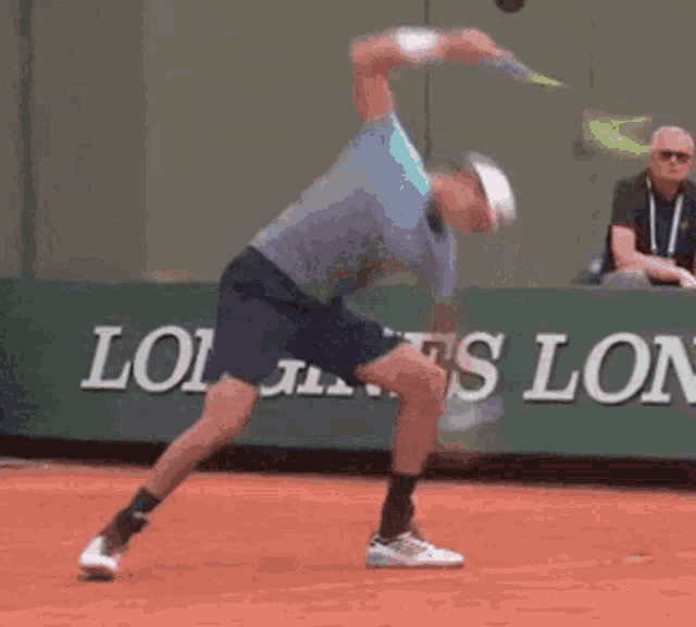 a man is playing tennis in front of a longines banner