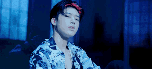 a young man with red hair is sitting in a dark room