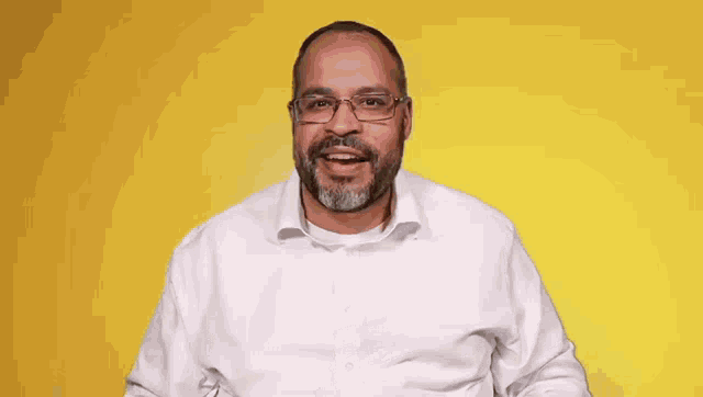 a man in a white shirt and glasses is holding a gold bar in front of his face .
