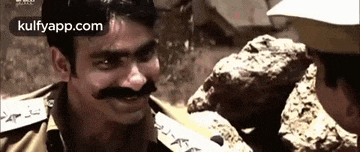 a man with a mustache is talking to a police officer .