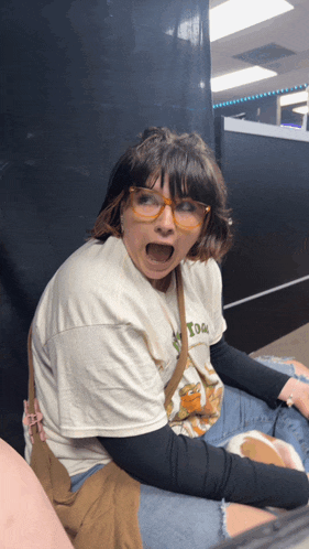 a woman wearing glasses and a t-shirt that says toon makes a funny face