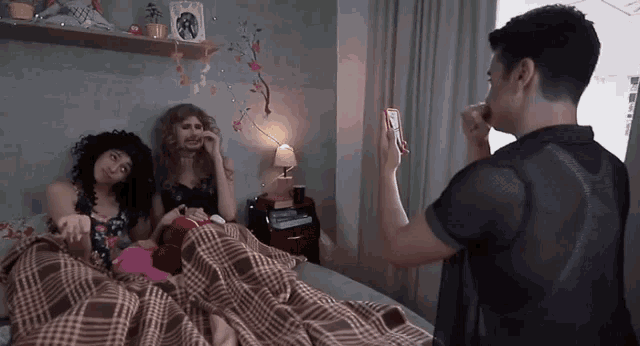 a man taking a picture of two women in a bedroom