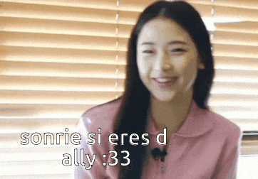 a woman is smiling in front of a window with blinds and the words sonrie si eres d ally 33 above her