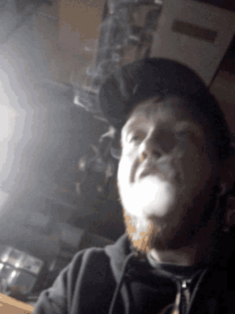 a man with a beard is smoking a cigarette with smoke coming out of his mouth