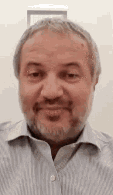 a man with a beard is wearing a striped shirt and smiling for the camera .