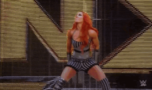 a woman with red hair is standing in front of a large screen .