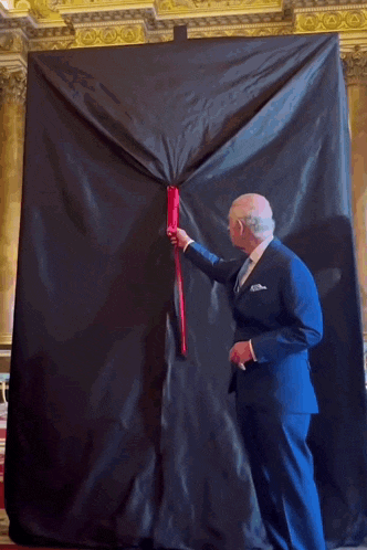 a man in a suit and tie is opening a black cloth