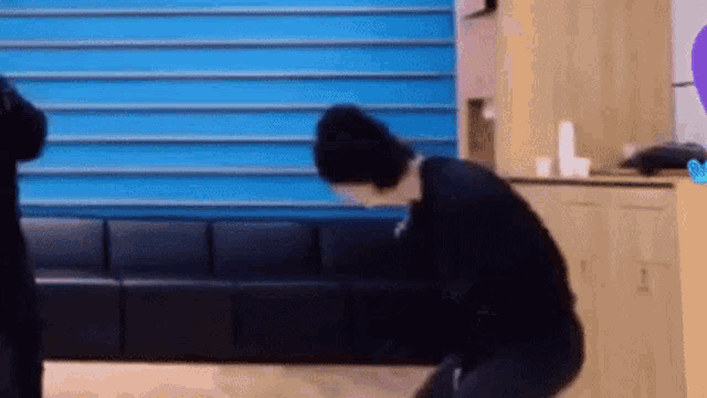 a man in a black sweater is kneeling down in a living room .