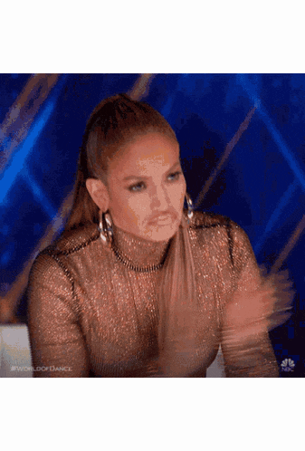 a woman in a gold dress is clapping her hands
