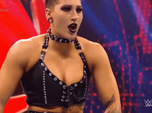 a woman is standing on a stage wearing a choker and a black top .