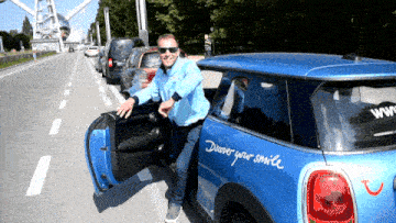 a man is getting out of a blue car that says " digger your smile " on the side