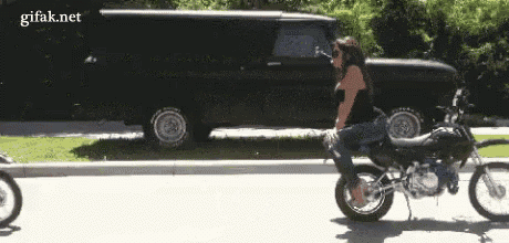 a woman is riding a motorcycle down a street next to a black truck .