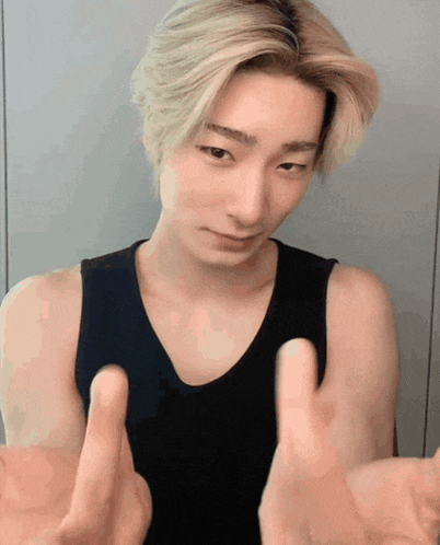 a young man in a black tank top is making a funny face with his hands outstretched