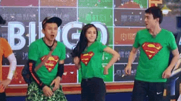 a group of people wearing green superman shirts are standing next to each other in front of a sign that says bingo .