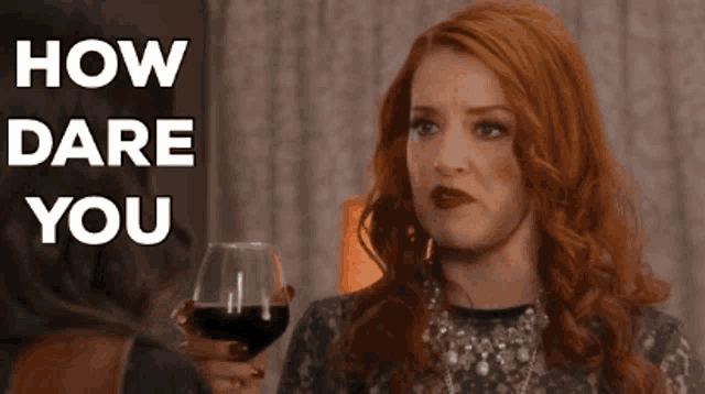 a woman with red hair is holding a glass of wine with the words how dare you above her