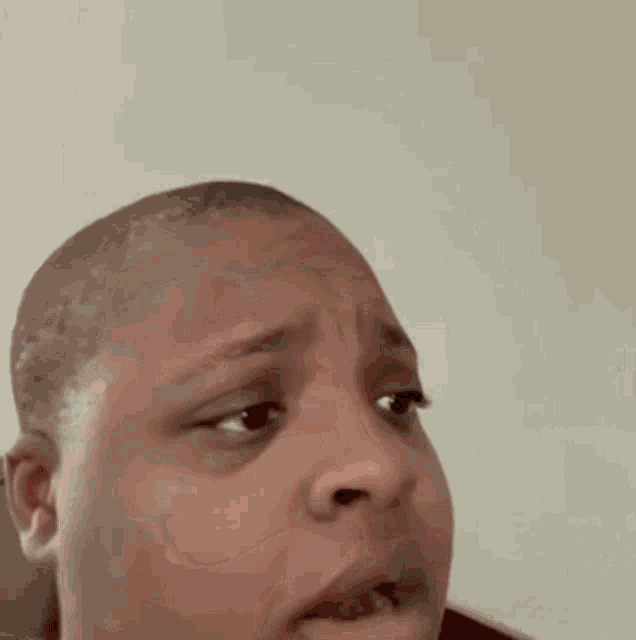 a close up of a man 's face with a shaved head and a serious look on his face .
