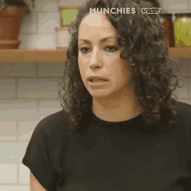 a woman with curly hair is making a funny face in a kitchen .