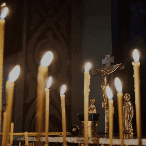 a row of candles are lit in front of a crucifix with jesus on it