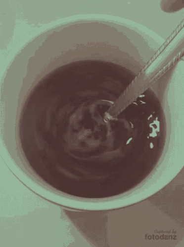 a cup of coffee with a spoon in it and the words created by fotodanz on the bottom