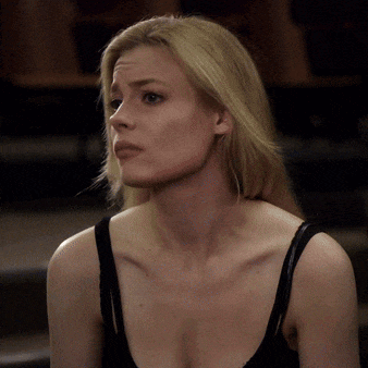 a blonde woman wearing a black tank top is looking at the camera