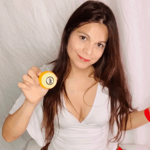 a woman in a white shirt holds a pool ball with the number 9 on it