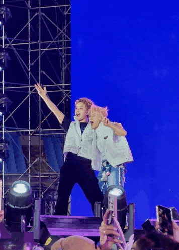 a couple of people standing on a stage with a blue backdrop