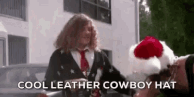 a man in a suit and tie is wearing a cowboy hat and a santa hat .
