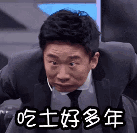 a man in a suit and tie is making a funny face with chinese writing .