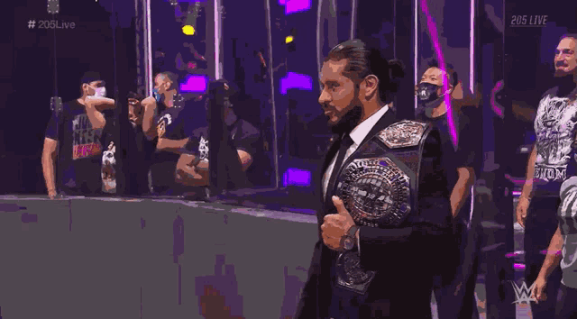 a man in a suit is holding a world heavyweight wrestling championship