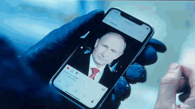 a person holding a cell phone with a picture of putin on it
