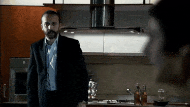 a man in a suit stands in front of a stove