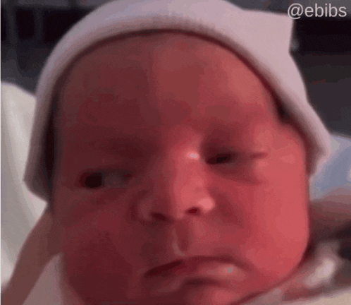a baby wearing a white hat is being held by a person