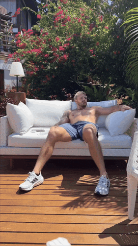 a shirtless man sits on a couch with his legs crossed