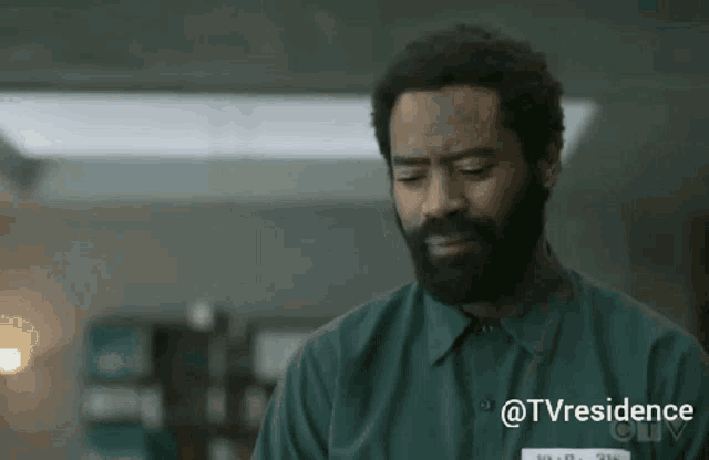 a man with a beard is wearing a green shirt with a tag that says tvresidence on it