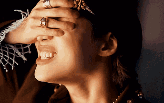 a woman with a ring on her finger is covering her face with her hand