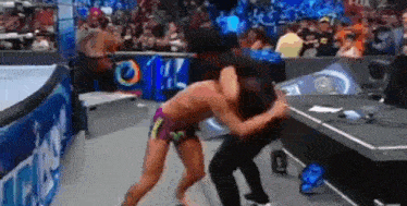 two men are wrestling in a wrestling ring while a crowd watches .