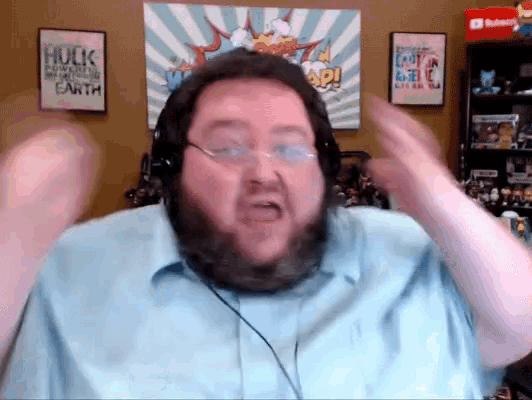 a man wearing headphones is making a funny face in front of a hulk poster on the wall