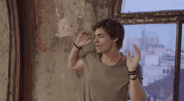 a man stands in front of a window with his hands up